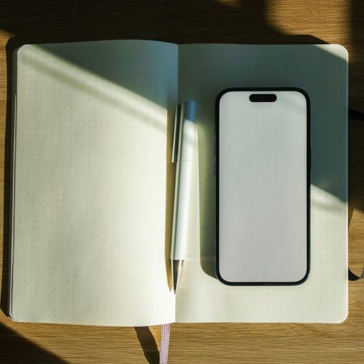 Smartphone, notebook and pen neatly arranged on a wooden desk