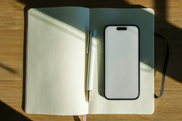 Smartphone, notebook and pen neatly arranged on a wooden desk